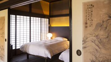 Un dormitorio de estilo japonés tradicional con suelo de tatami, una cama baja y puertas correderas.
