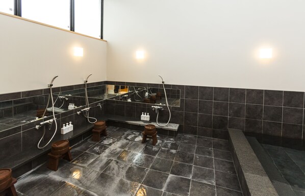 Un baño moderno con varios lavamanos, un espejo grande y suelo con calefacción.