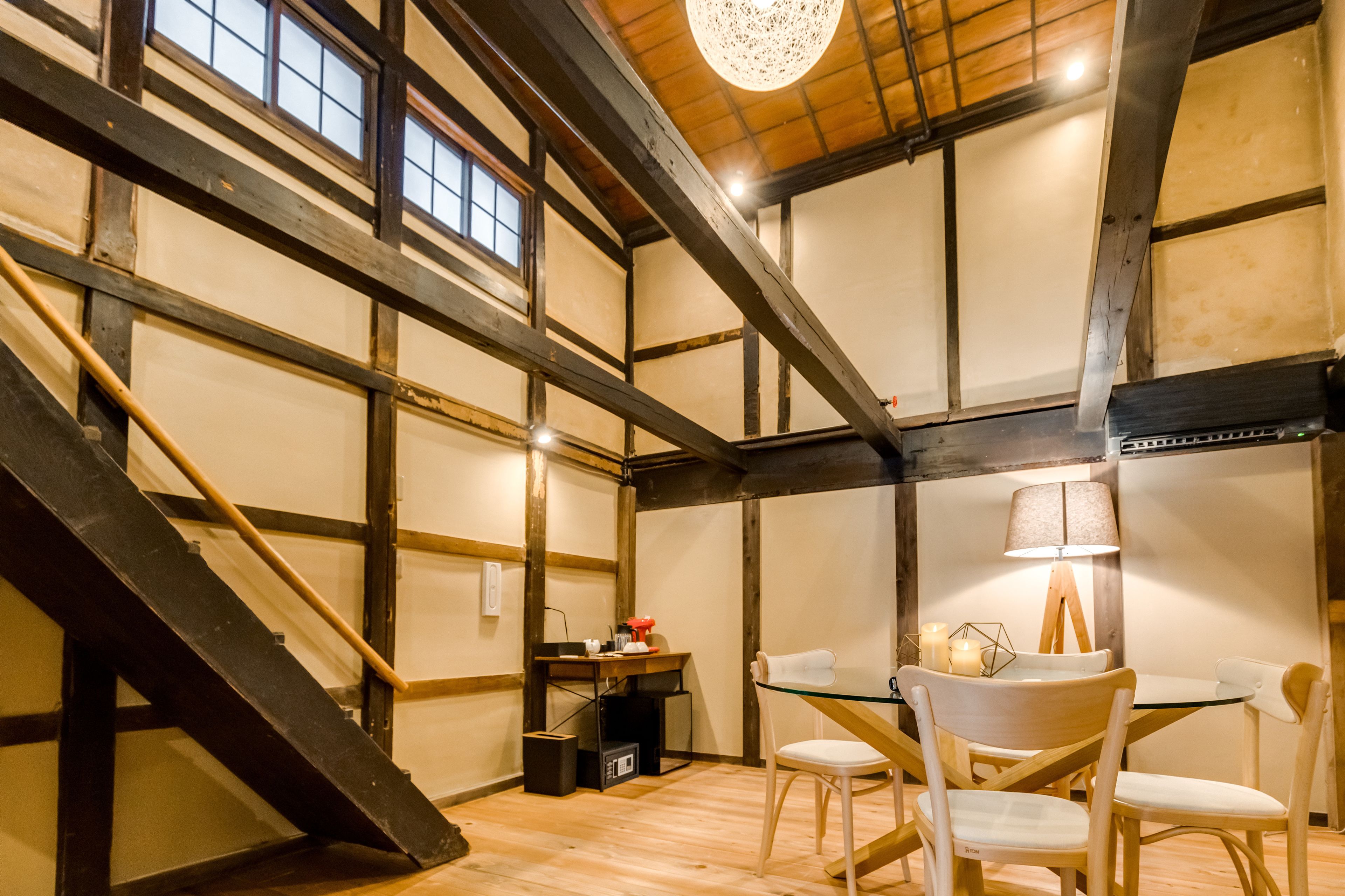 A dining area with a table and chairs, a lamp, and a staircase.
