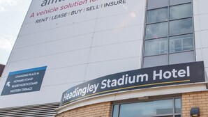 Un edificio con un cartel grande para 'amt.co.uk' y un cartel para 'Headingley Stadium Hotel'.