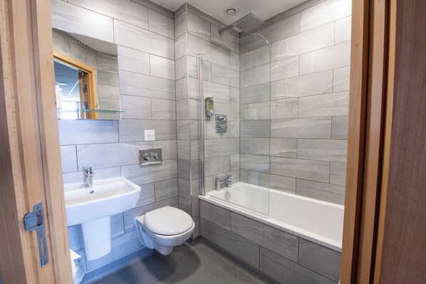 A modern bathroom with a sink, toilet, and bathtub.