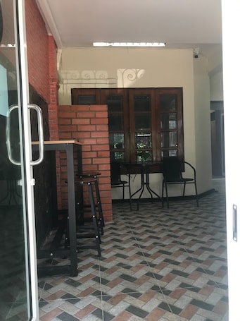 A room with a tiled floor, a brick wall, a wooden door, and a table with chairs.