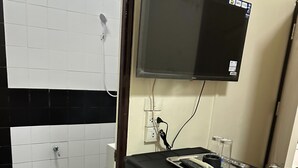 A compact kitchenette with a refrigerator, a microwave, and a small countertop. - Orchid House (Bangkok)