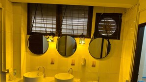 A bathroom with three sinks, two mirrors, and a window with blinds. - Orchid House (Bangkok)