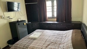 A hotel room with a bed, a desk, a television, and a window with curtains. - Orchid House (Bangkok)