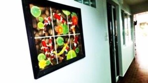 Un pasillo con una obra de arte colgada en la pared, que presenta una cuadrícula de formas abstractas y coloridas.