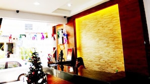 Una zona de recepción con pared de piedra, un árbol de Navidad y un mostrador.