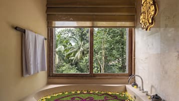 A bathroom with a large window, a bathtub with a floral design, and a towel rack.