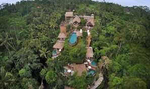 A tropical resort with multiple thatched-roof buildings, swimming pools, and lush greenery. - The Kayon Resort (Ubud)