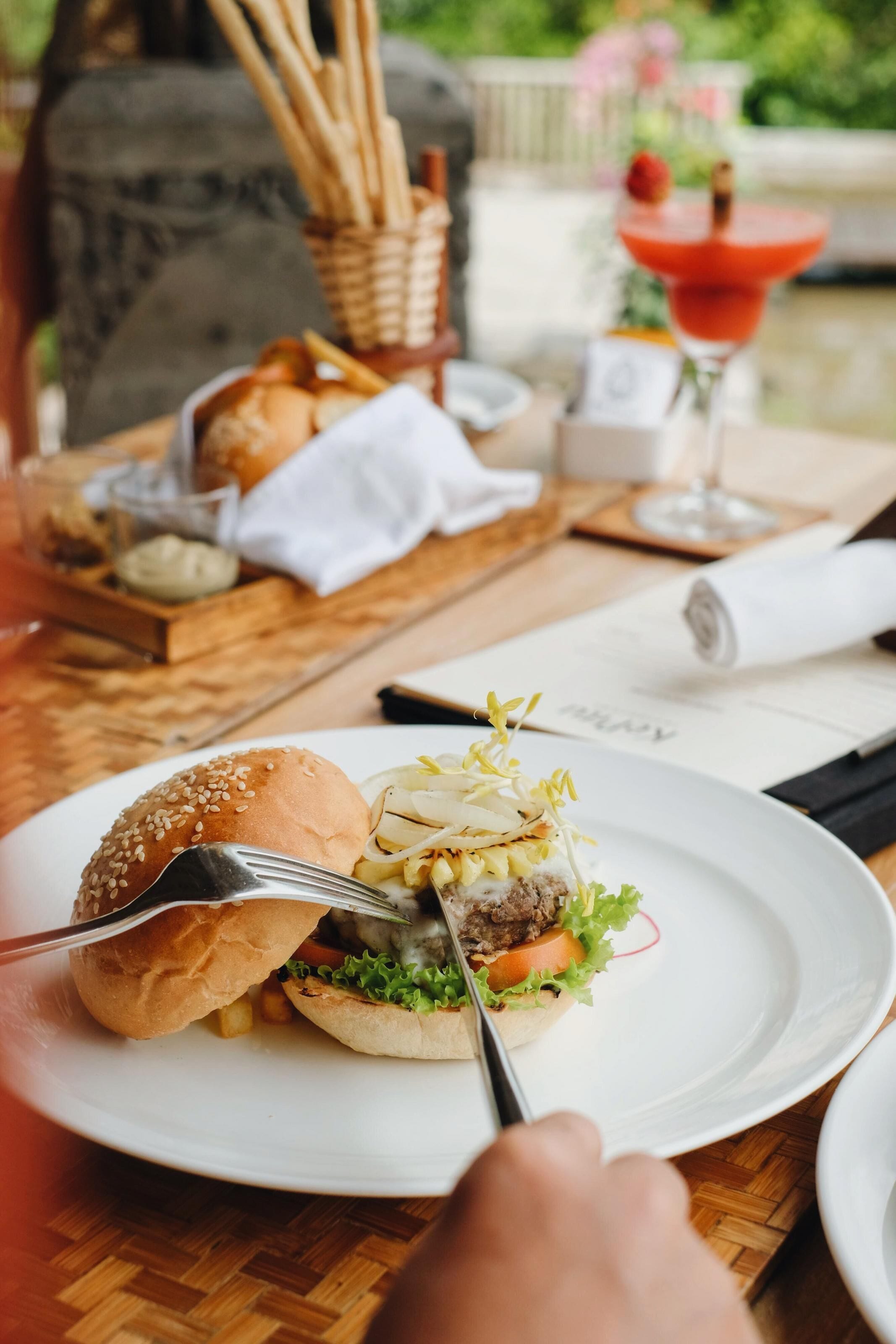 Ein Esstisch mit einer Mahlzeit bestehend aus einem Burger, Brot und einem Getränk.