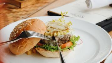 Ein Esstisch mit einer Mahlzeit bestehend aus einem Burger, Brot und einem Getränk.