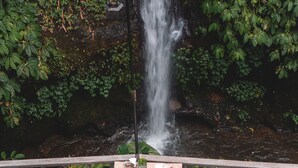 A wooden deck with a table set for two, overlooking a waterfall. - The Kayon Resort (Ubud)