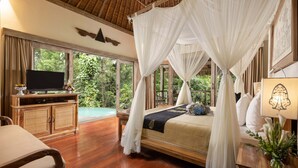 A spacious bedroom with a large bed, a television, and a view of lush greenery. - The Kayon Resort (Ubud)