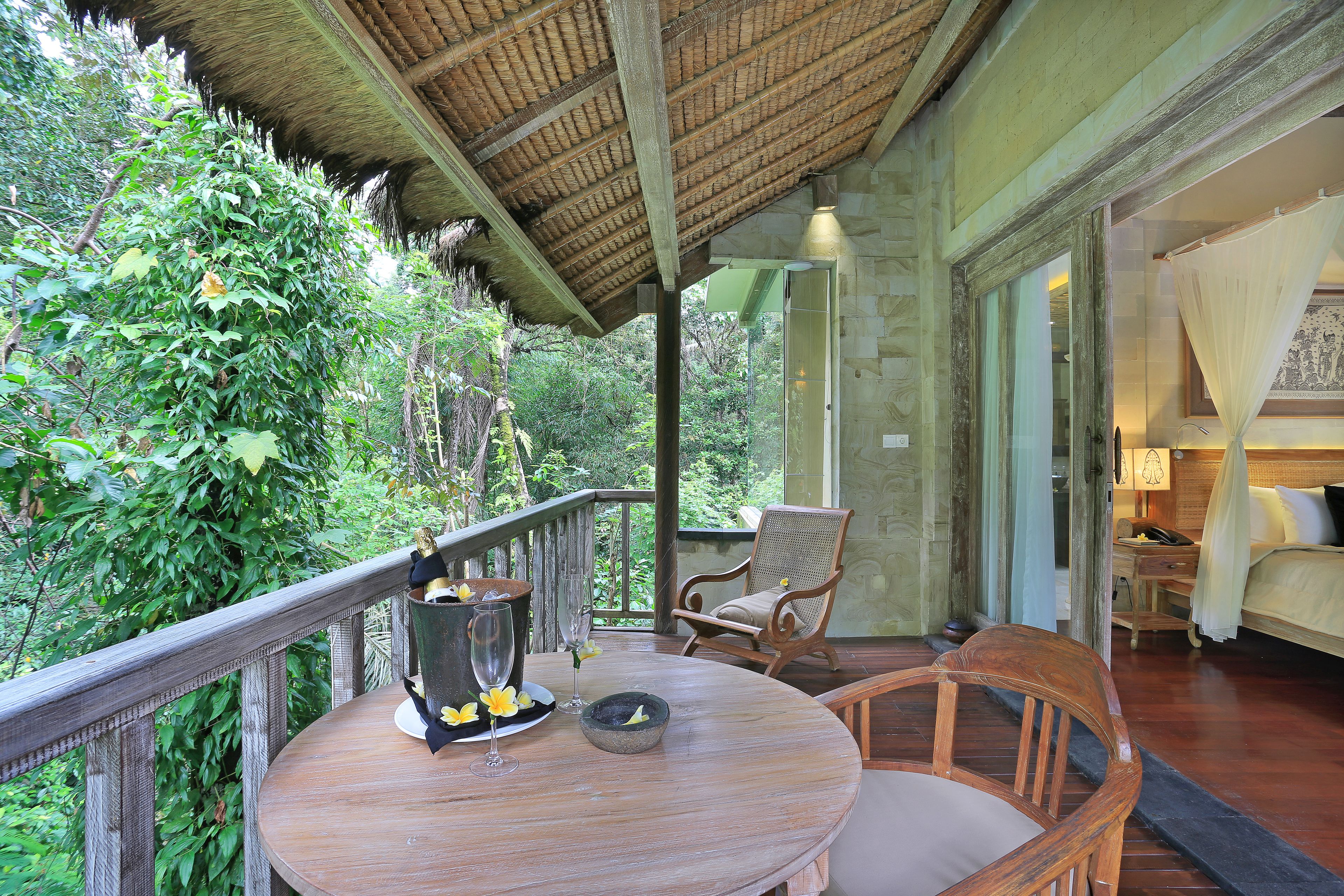 Une terrasse en bois avec une table, des chaises et une vue sur une végétation luxuriante.