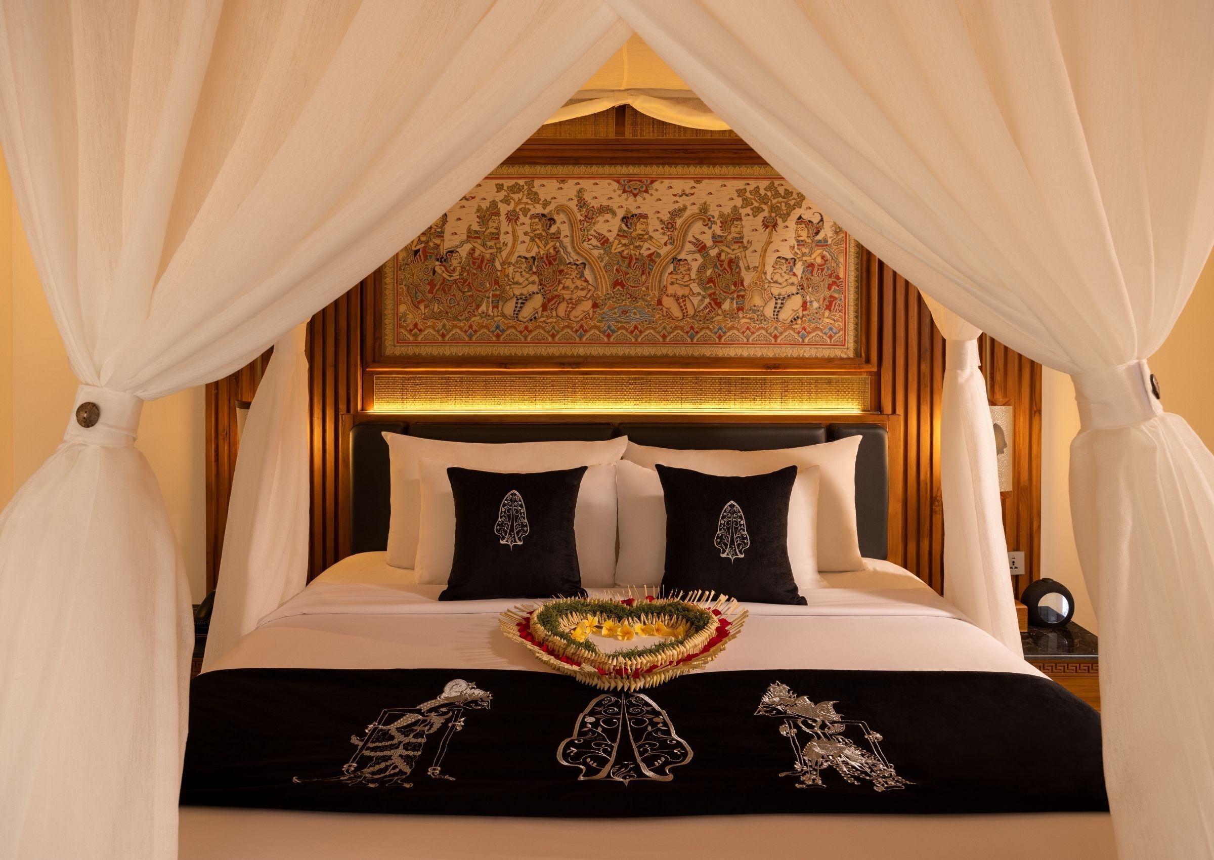 Una cama con dosel, cabecera con un mural detallado y una colcha decorativa.