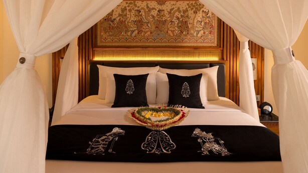 Una cama con dosel, cabecera con un mural detallado y una colcha decorativa.
