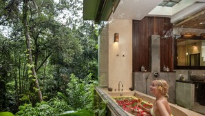 A woman in a bathtub filled with water and flowers, surrounded by lush greenery. - The Kayon Resort (Ubud)