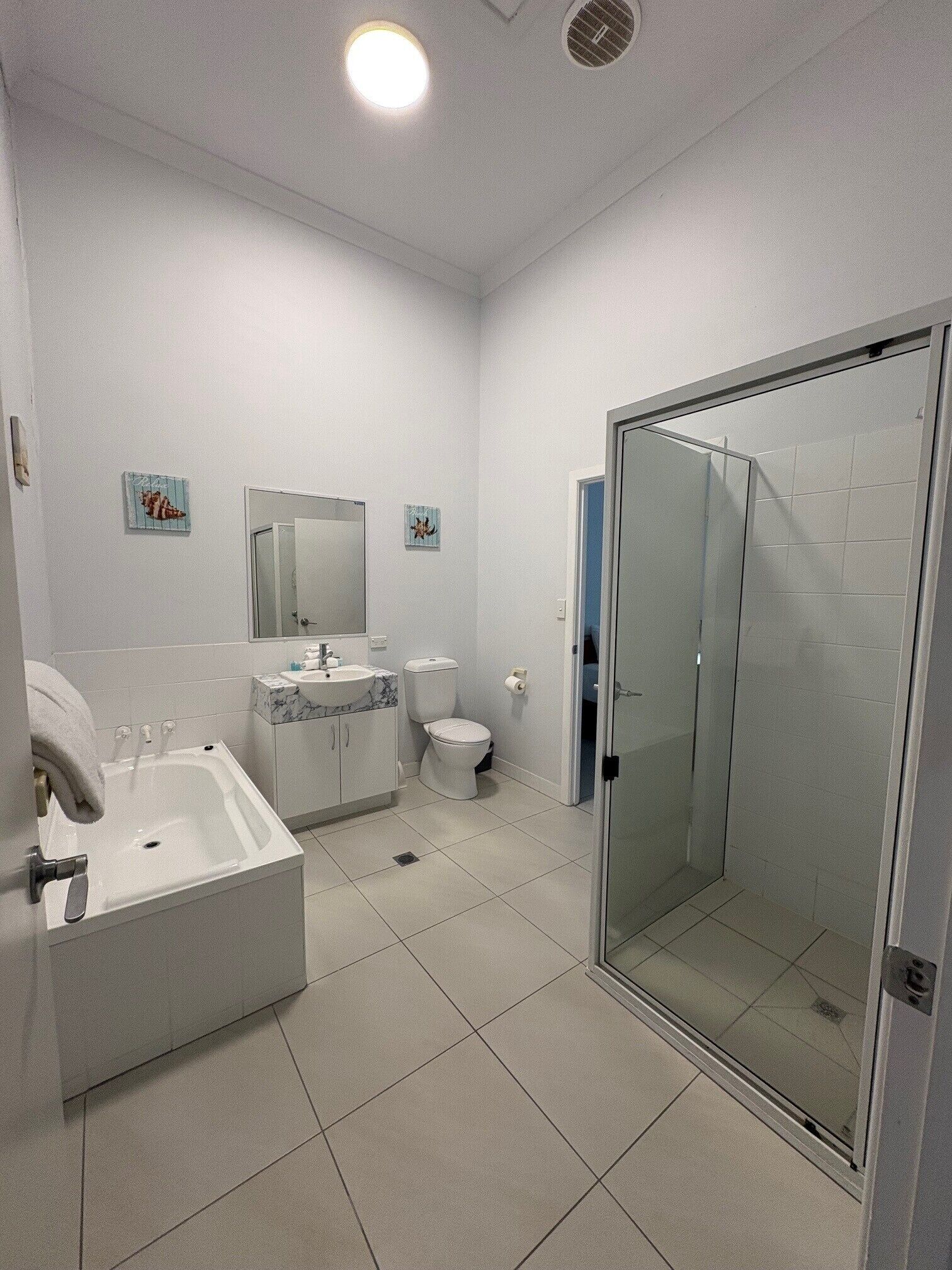 A modern bathroom with a bathtub, toilet, and glass-enclosed shower.