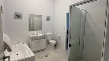 A modern bathroom with a bathtub, toilet, and glass-enclosed shower.