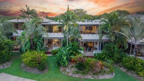 Uma casa moderna de dois andares com jardim, janelas amplas e telhado plano.