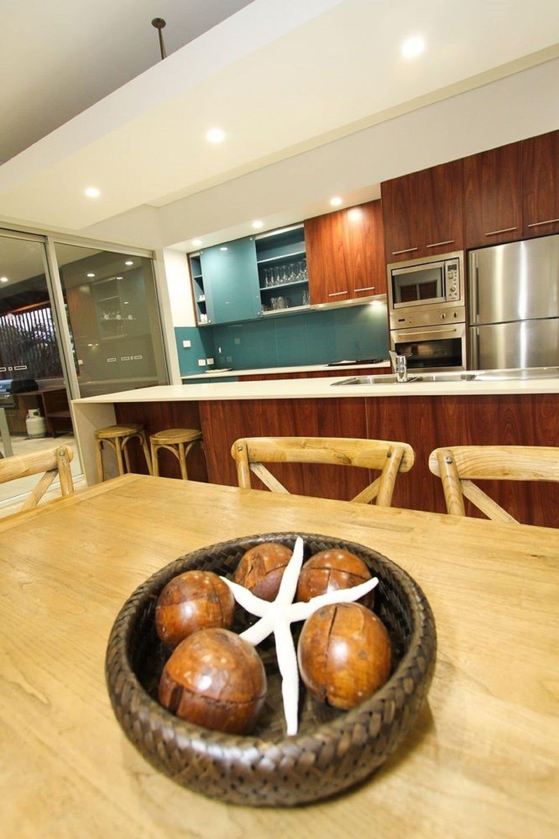 A modern kitchen with wooden cabinets, stainless steel appliances, and a dining area with a wooden table and chairs.
