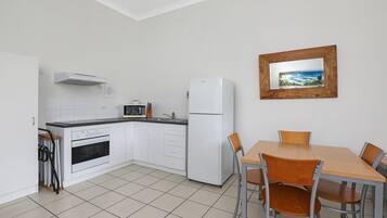 A kitchen with white cabinets, a microwave, a refrigerator, and a dining table with chairs.