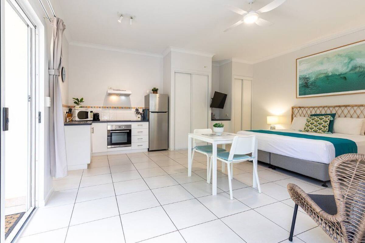 A compact room with a kitchenette, a dining area, and a bed.