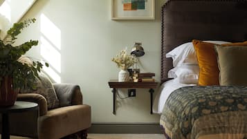 Une chambre à coucher avec un grand lit, une table de chevet avec une lampe, une chaise et une plante en pot.