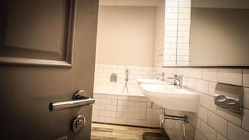 Un baño con lavamanos blanco, espejo y ducha.