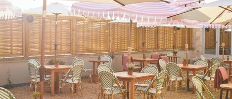 An outdoor seating area with striped umbrellas, wicker chairs, and tables.