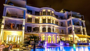 A multi-story hotel with a pool area, outdoor seating, and a well-lit entrance. - Panorama De Luxe (Odesa)