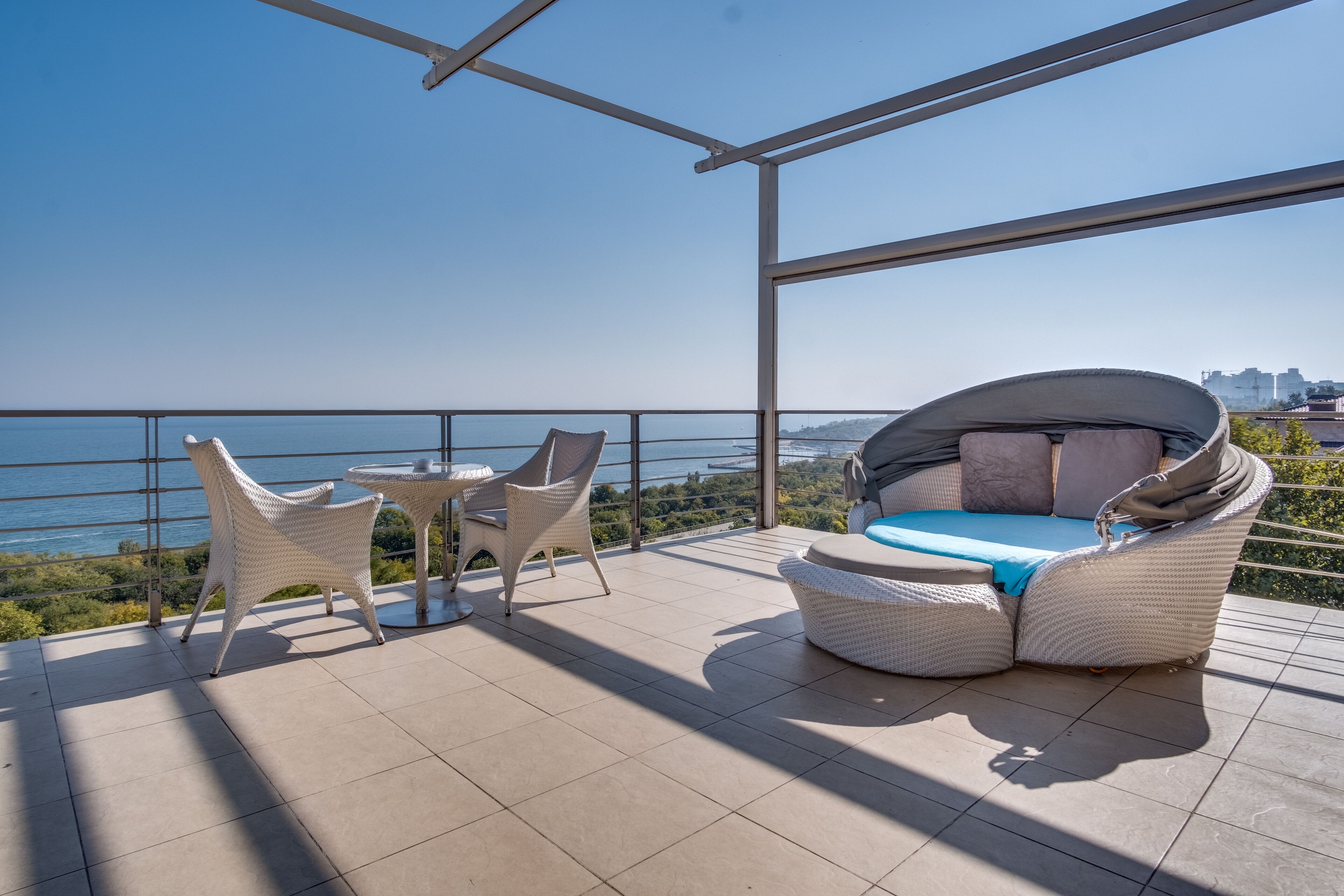 Un balcon doté de meubles en osier, d’une table et offrant une vue sur la mer.