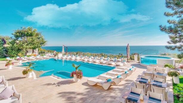 A pool area with lounge chairs and a view of the sea. - Panorama De Luxe (Odesa)