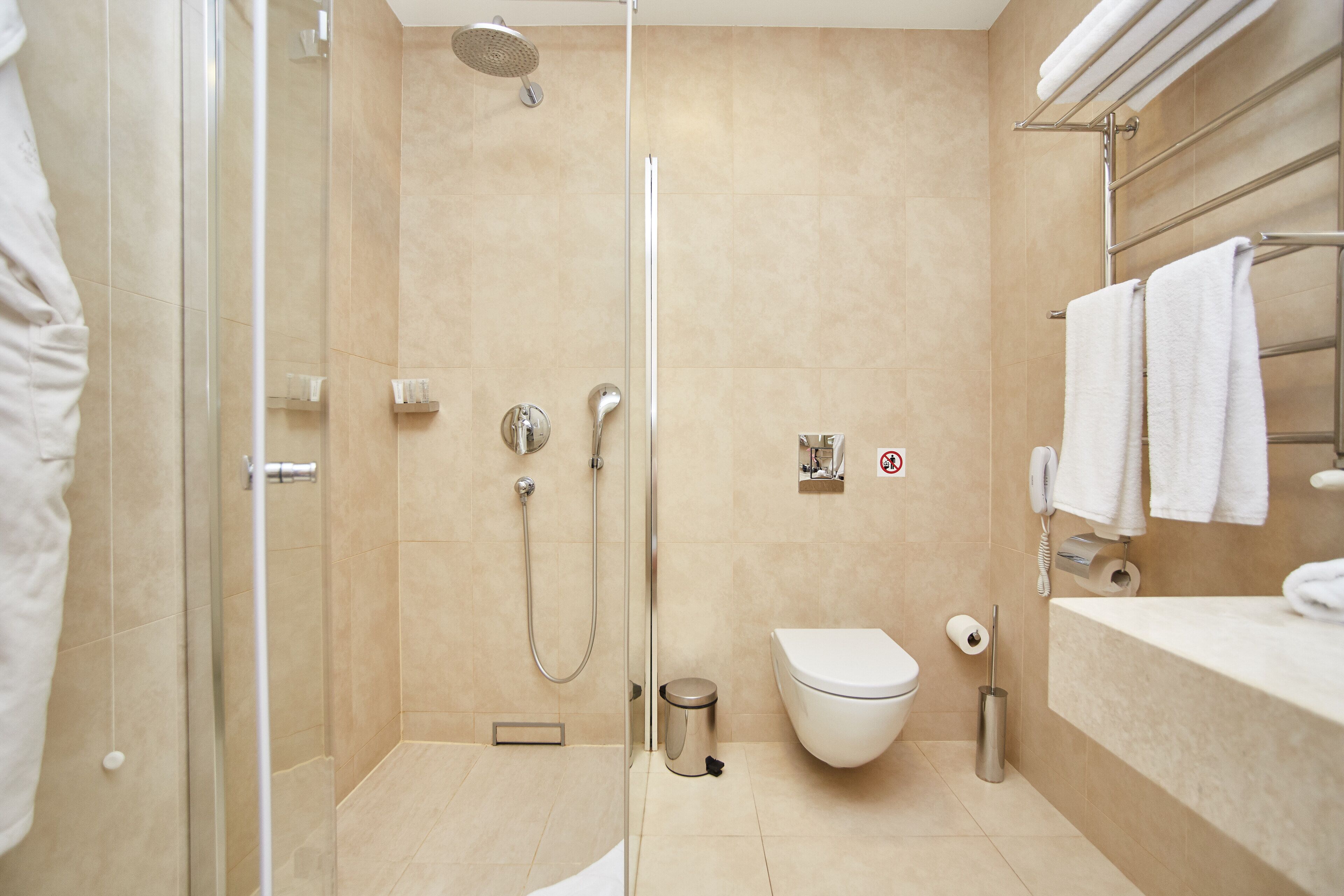A modern bathroom with a glass-enclosed shower, a toilet, and a vanity with a towel rack.