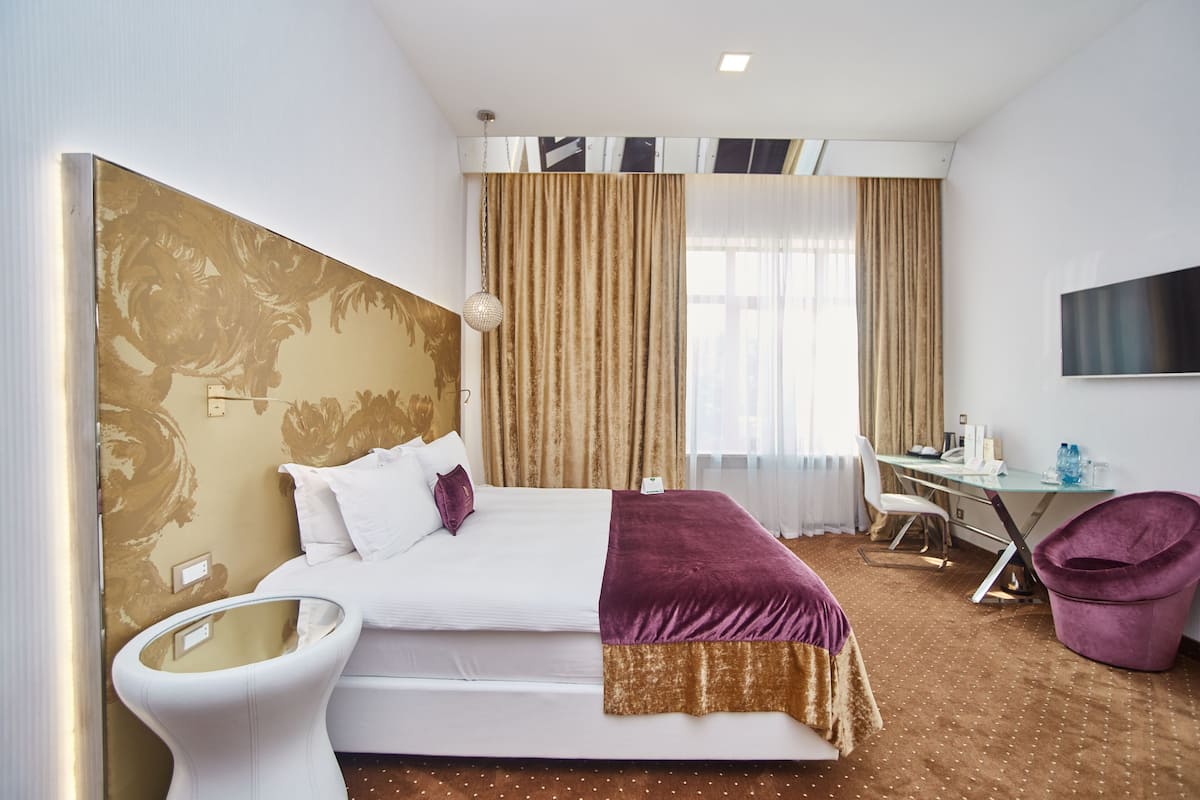A hotel room with a bed, a desk, a chair, and a television.