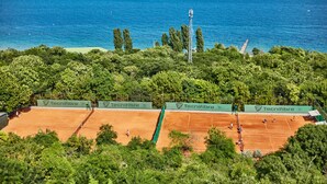 An outdoor tennis court with a view of the sea and trees. - Panorama De Luxe (Odesa)
