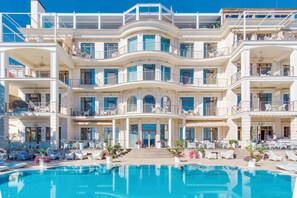 Un hotel grande de varios pisos con una zona de piscina al frente.