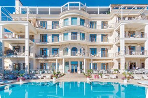 Un hotel grande de varios pisos con una zona de piscina al frente.