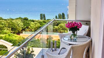 Un balcone con ringhiera in vetro che si affaccia su una vista panoramica del mare e del verde.