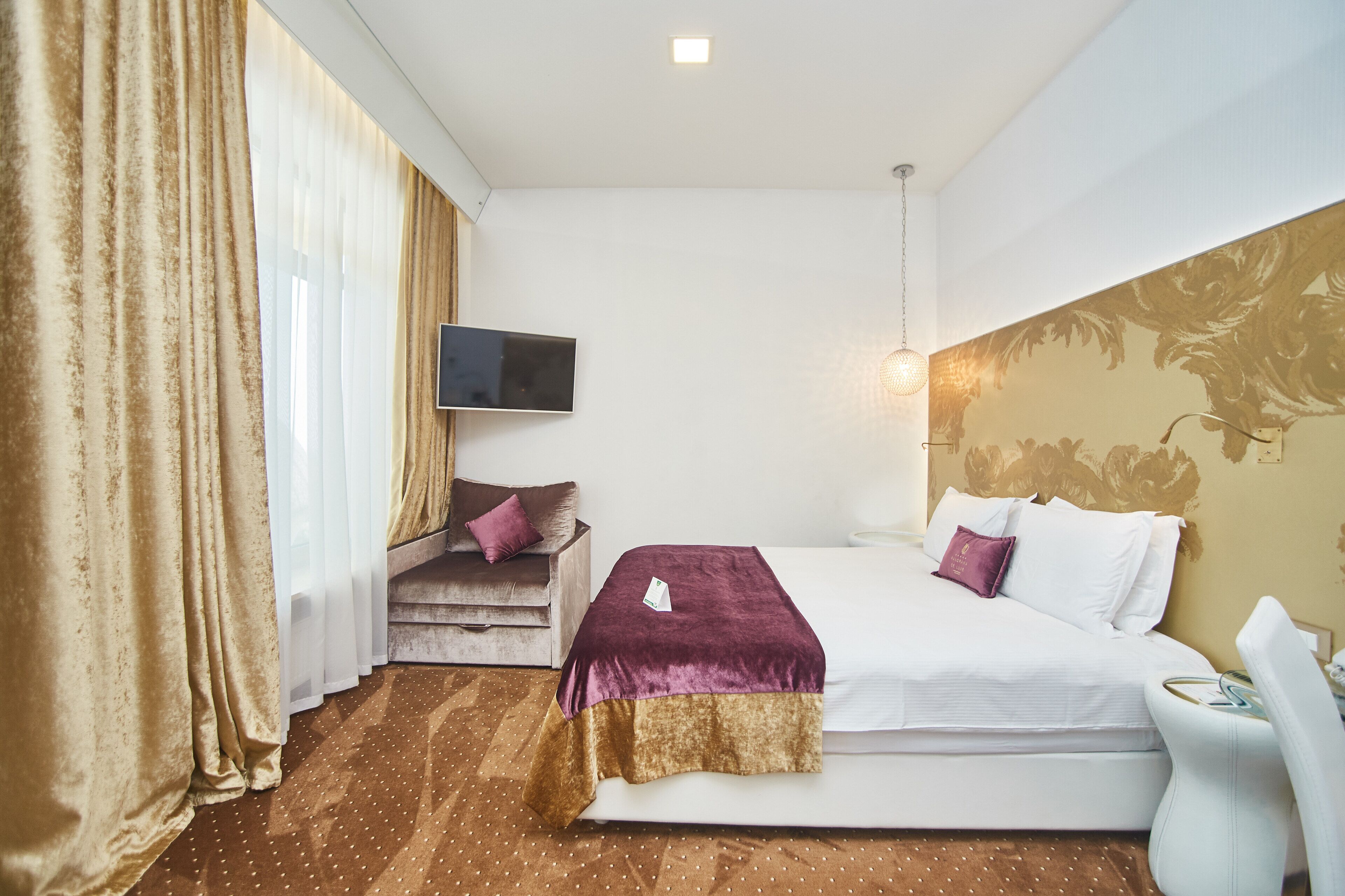 Una camera d'albergo con un letto, una TV, una scrivania e una sedia.