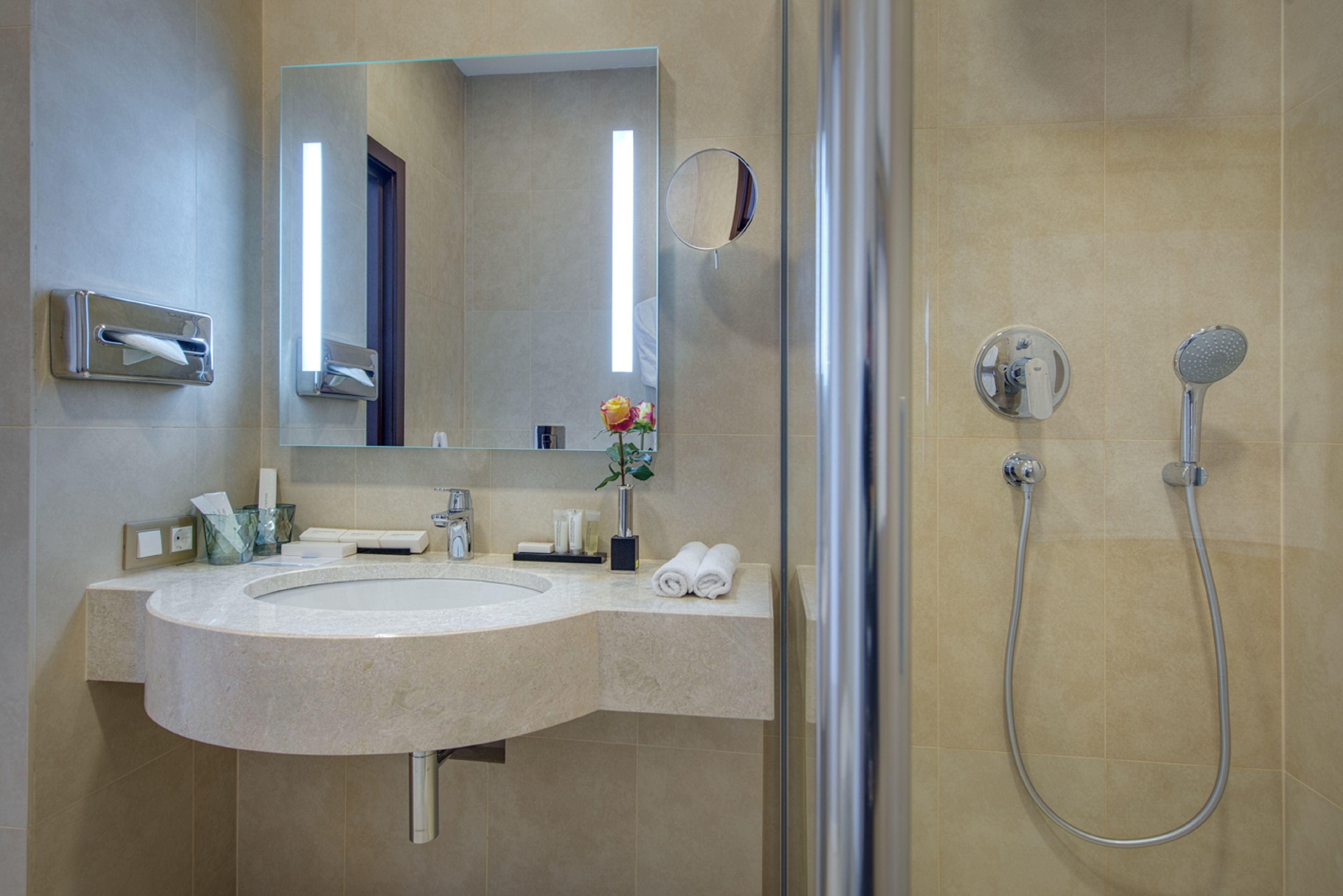 Une salle de bain moderne avec un grand lavabo, un miroir, une douche et un porte-serviettes.