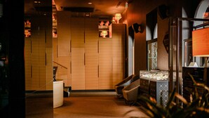 Un moderno vestíbulo de hotel con un mostrador de recepción de madera, una zona de estar y una vitrina de vidrio.