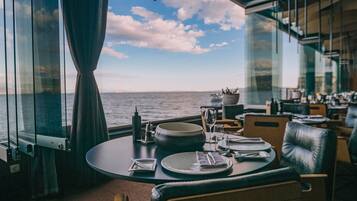A dining area with a table set for two, overlooking the sea.