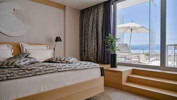 Une chambre moderne avec un grand lit, une table de chevet, une plante en pot et une vue sur l’extérieur grâce à une grande fenêtre.