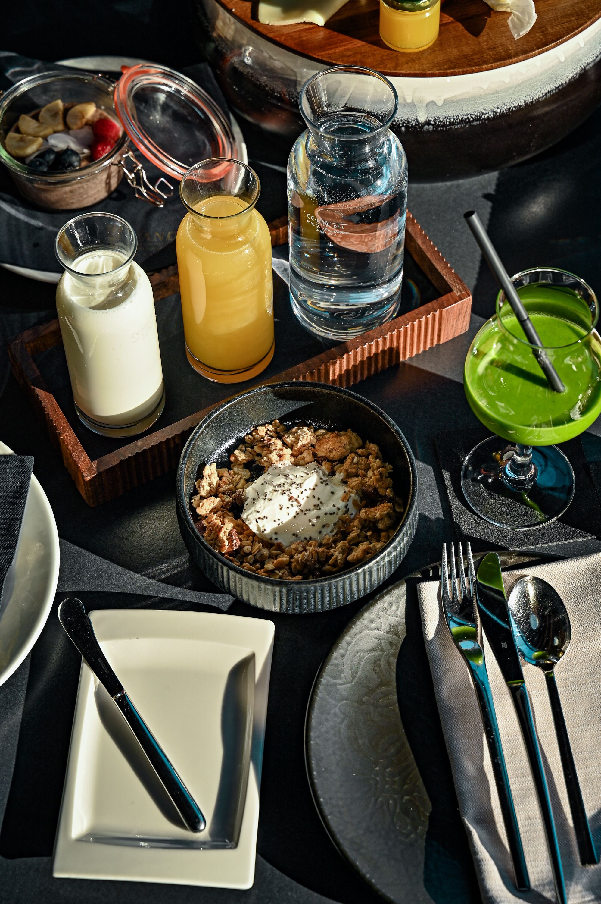 A breakfast setting with a bowl of cereal, a glass of orange juice, a glass of water, and a green drink on a tray.