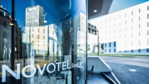 A hotel sign with the name "NOVOTEL Basel City" and a reflection of the cityscape. - Novotel Basel City (Basel)