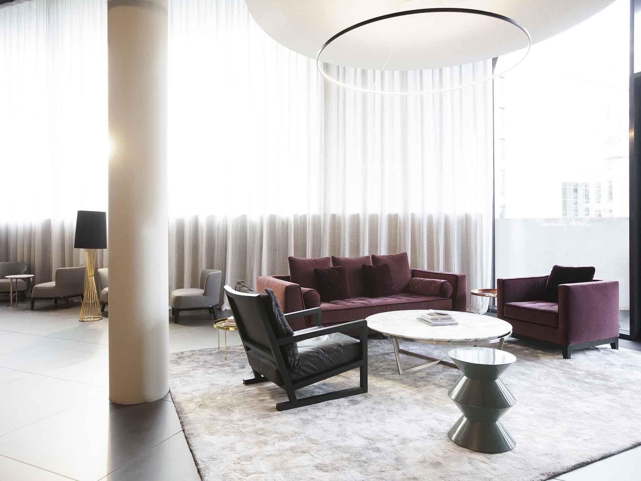 Ein modernes Wohnzimmer mit einer Couch, Sesseln, einem Couchtisch und einer Stehlampe.