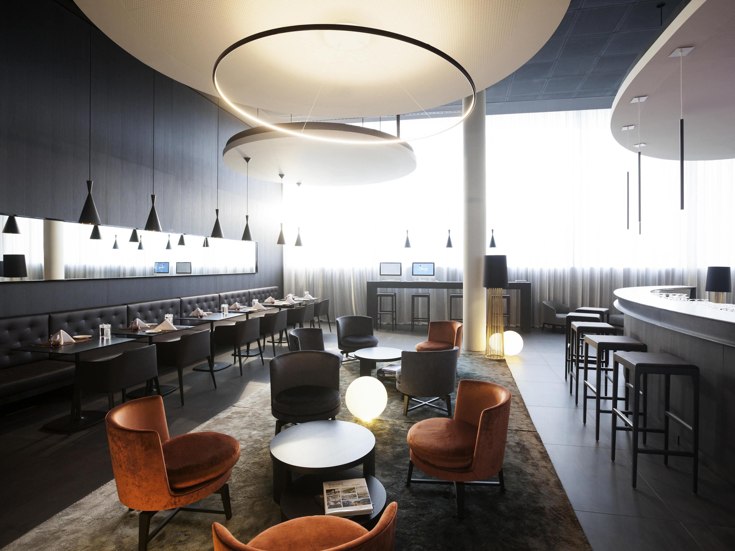 A modern hotel lobby with a bar area, seating arrangements, and a large window providing natural light.