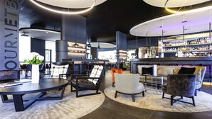 A modern bar area with seating and a well-stocked bar. - Novotel Basel City (Basel)