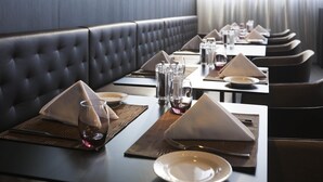 A restaurant with a long table set with plates, glasses, and cutlery. - Novotel Basel City (Basel)